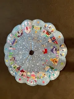 Designs by JuJu Christmas tree skirt: Blue quilted tree skirt with whimsical embroidered Christmas village scene. - Looney Bin Quilting